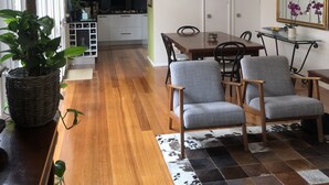 Eine moderne Küche mit weißen Schränken, einer Edelstahl-Dunstabzugshaube und einem Essbereich mit Holztisch und grau gepolsterten Stühlen.