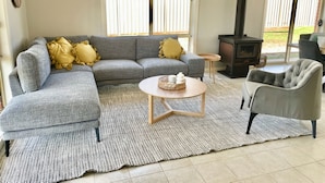 Un salon avec un canapé d’angle, une table basse ronde et une cheminée.