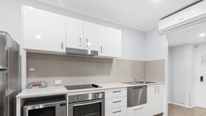 A modern kitchen with white cabinetry, stainless steel appliances, and a built-in dishwasher.