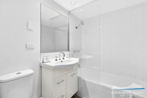 A modern bathroom with a large mirror, a sink, a toilet, and a shower. - One Bedroom Unit in the Heart of Kangaroo Point (Kangaroo Point)