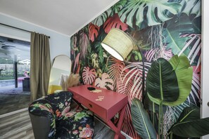 A room with a desk, a lamp, and a large tropical plant wall. - Tropical 5BR Pool Beach House - 5min from Beaches! (Seminole)
