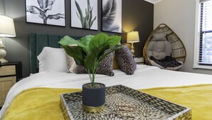 A neatly made bed with a yellow bedspread, a decorative tray with the phrase "SPEND THE WEEK HERE" on it, and a potted plant on the bed. - Tropical 5BR Pool Beach House - 5min from Beaches! (Seminole)