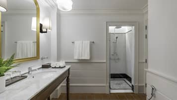 A modern bathroom with a large mirror, two wall-mounted lights, a sink, a vanity, and a shower area.
