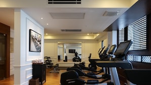 Une salle de sport équipée de tapis de course, de vélos elliptiques et de poids.