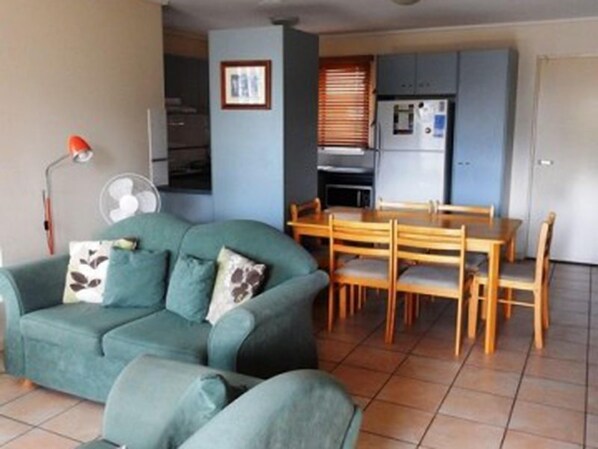 Een knus woongedeelte met een bank, een eettafel en een kitchenette.