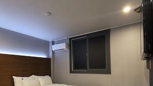 Een moderne slaapkamer met een bed, bureau en een flatscreen televisie.
