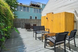 An outdoor patio area with a wooden deck, metal chairs, and a wooden fence.