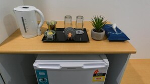 A kitchenette with a coffee maker, a small fridge, a plant, and a water dispenser on a wooden countertop. - Birch Resort Port Douglas (Port Douglas)