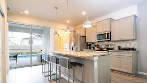 Una cocina moderna con una isla grande, electrodomésticos de acero inoxidable y vistas a un jardín trasero.