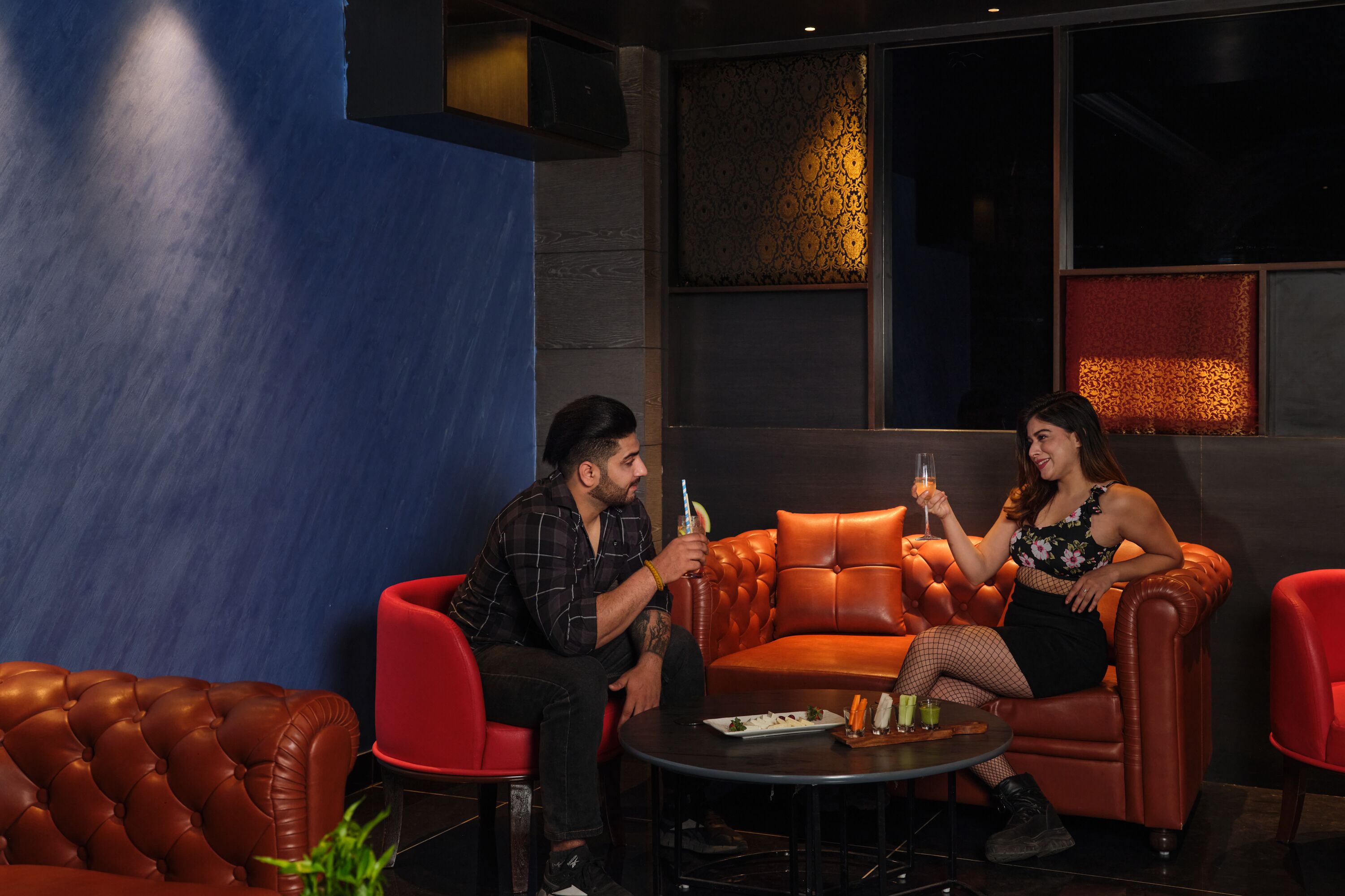Un espace détente moderne avec des canapés en cuir, une petite table ronde avec des boissons et un mur décoratif.