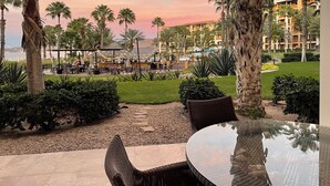 Eine Resort-Terrasse mit Sitzgelegenheiten im Freien, Palmen und Blick aufs Meer.
