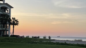 Ein Strandgrundstück mit einem großen Gebäude, Palmen und Blick auf den Ozean.