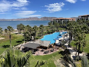 Un resort con una amplia piscina, palmeras y vistas al mar.