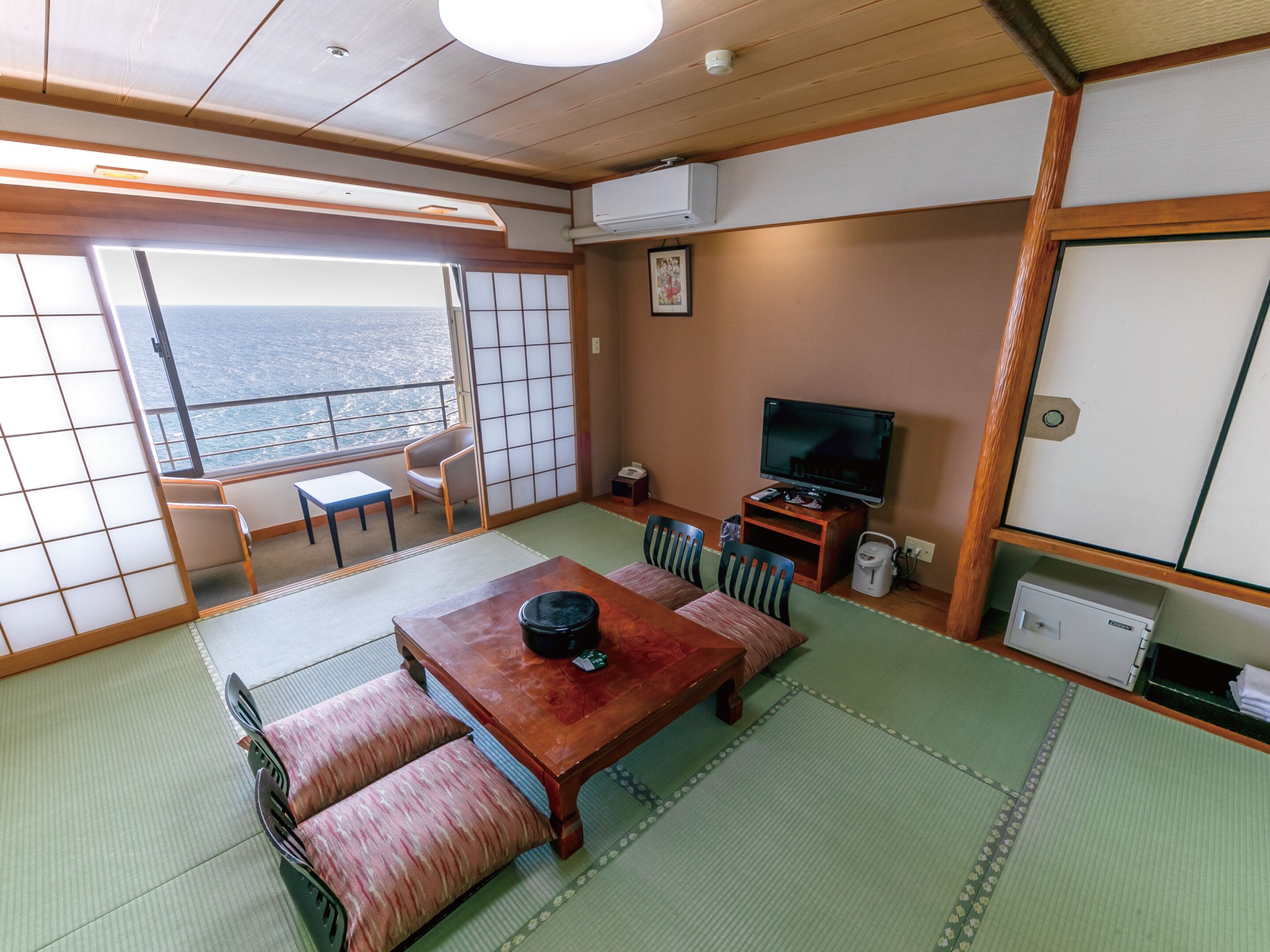 A traditional Japanese-style room with tatami flooring, a low wooden table, and a television.
