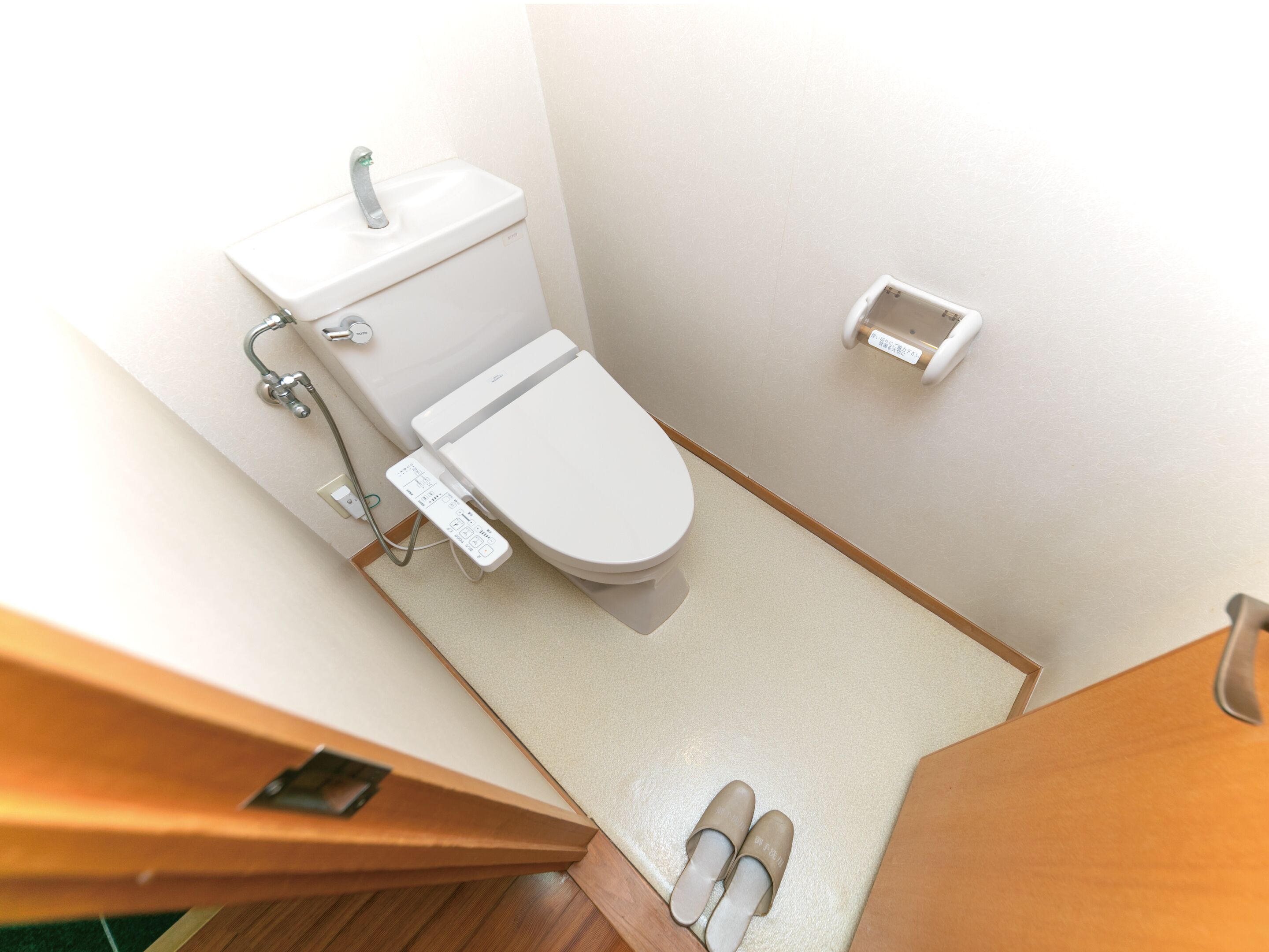 Een compacte, moderne badkamer met toilet, bidet en een klein kastje.