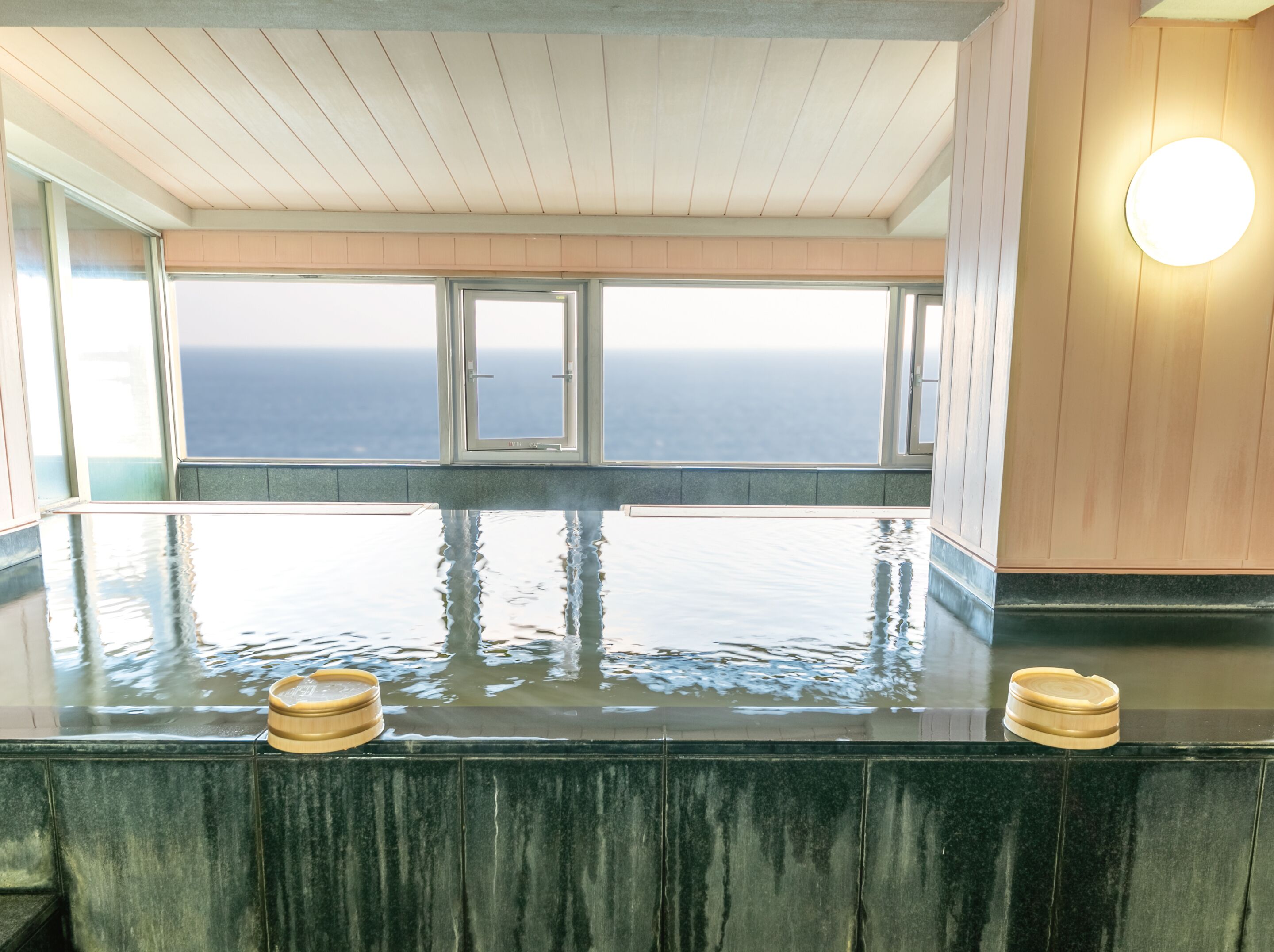Un spa con una gran piscina interior, techo de madera y vistas al océano.