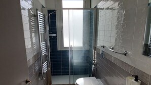 Ett modernt badrum med dusch, två toaletter, ett stort handfat och en spegel.