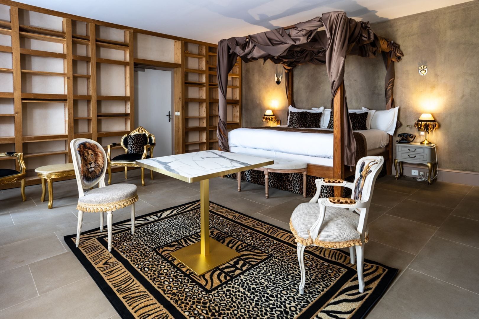 Un dormitorio con cama con dosel, un escritorio con sillas, un tapete estampado de cebra y una estantería.