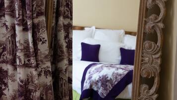 A bedroom with a bed, pillows, and a framed mirror reflecting the room.