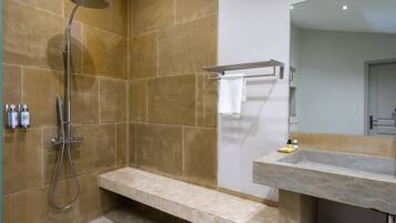 Un baño con ducha, banco, lavamanos y espejo.
