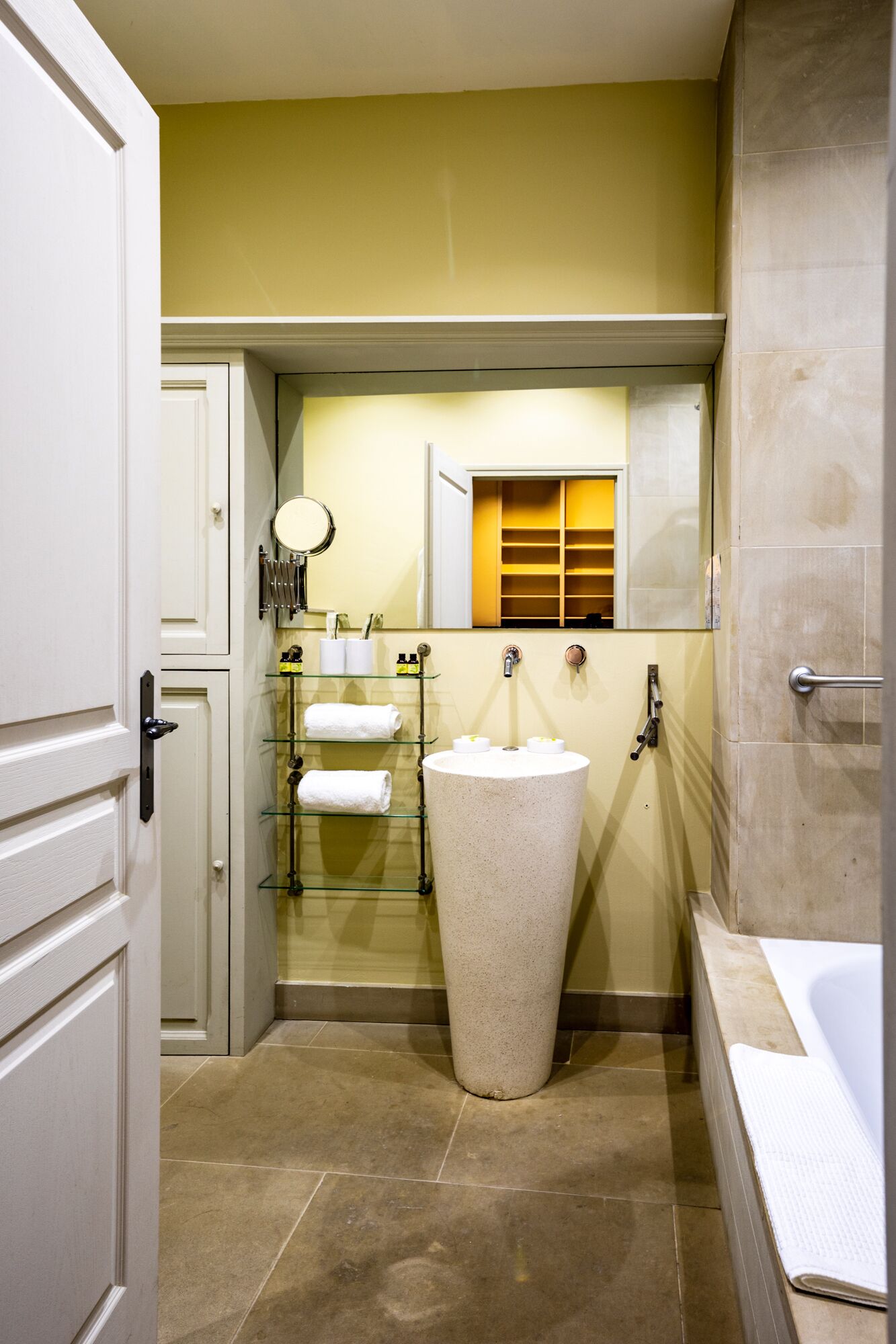 A bathroom with a freestanding sink, a mirror, and a towel rack.