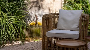 A wicker chair with a white cushion in a garden setting. - Le Clos Violette D'Aglaé (L'Isle-sur-la-Sorgue)