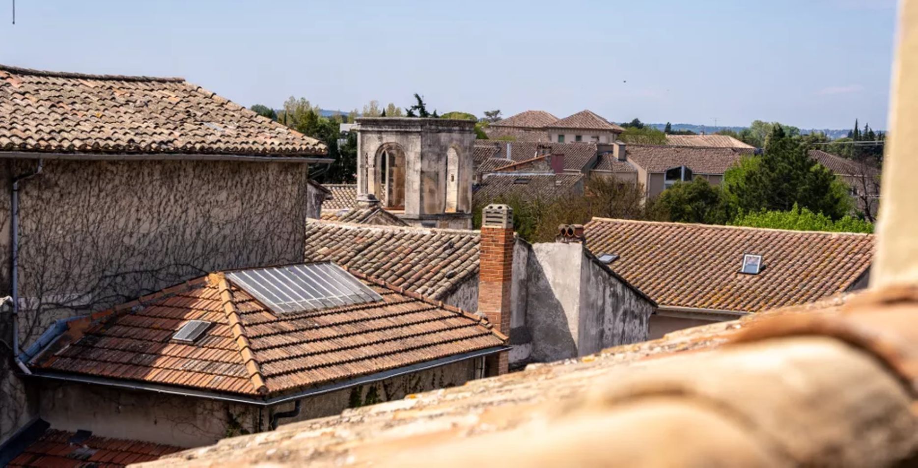 A view of a historic town with traditional buildings, including a prominent stone tower and a church with a bell tower.
