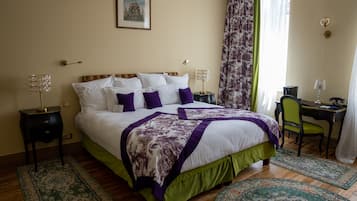 A neatly arranged bedroom with a large bed, a desk, and a chair.