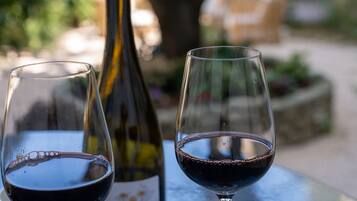 Two wine glasses on a table with a bottle of wine in the background.