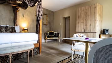 Ein Hotelzimmer mit einem Bett, einer Couch, einem Esstisch, einem Stuhl, einem Spiegel und einem Kleiderschrank.