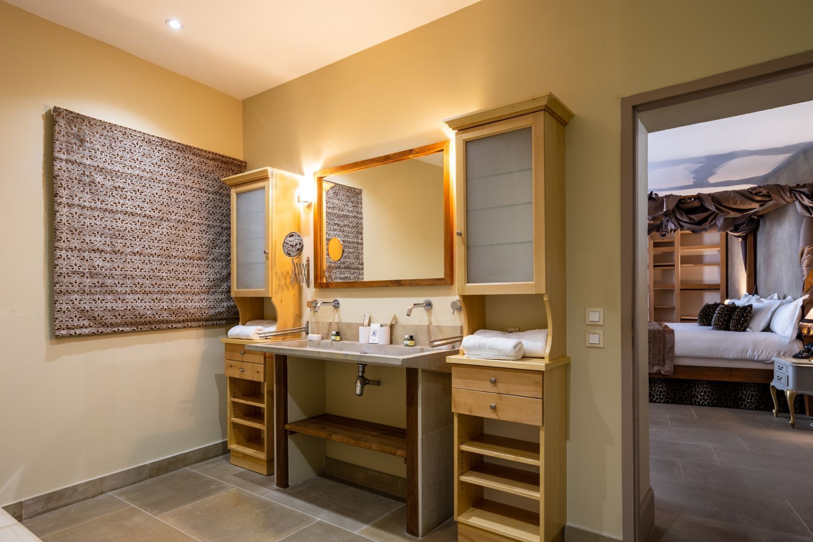 Un baño moderno con lavamanos doble, tocador y un espejo grande. Se ve una zona de ducha al fondo.