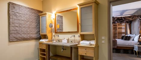 Un baño moderno con lavamanos doble, tocador y un espejo grande. Se ve una zona de ducha al fondo.