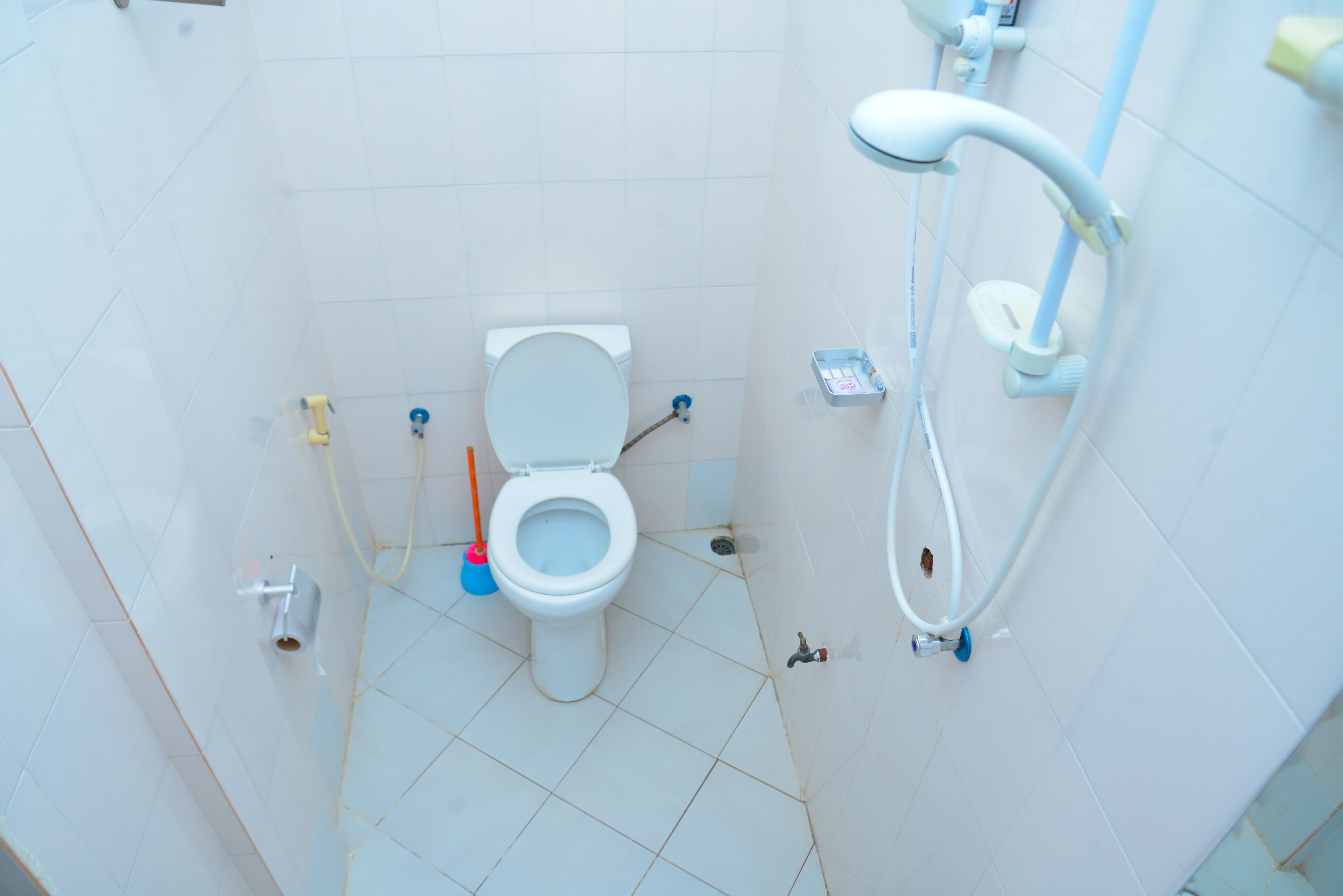 Un baño pequeño con azulejos, un inodoro, una ducha y un secador de manos.