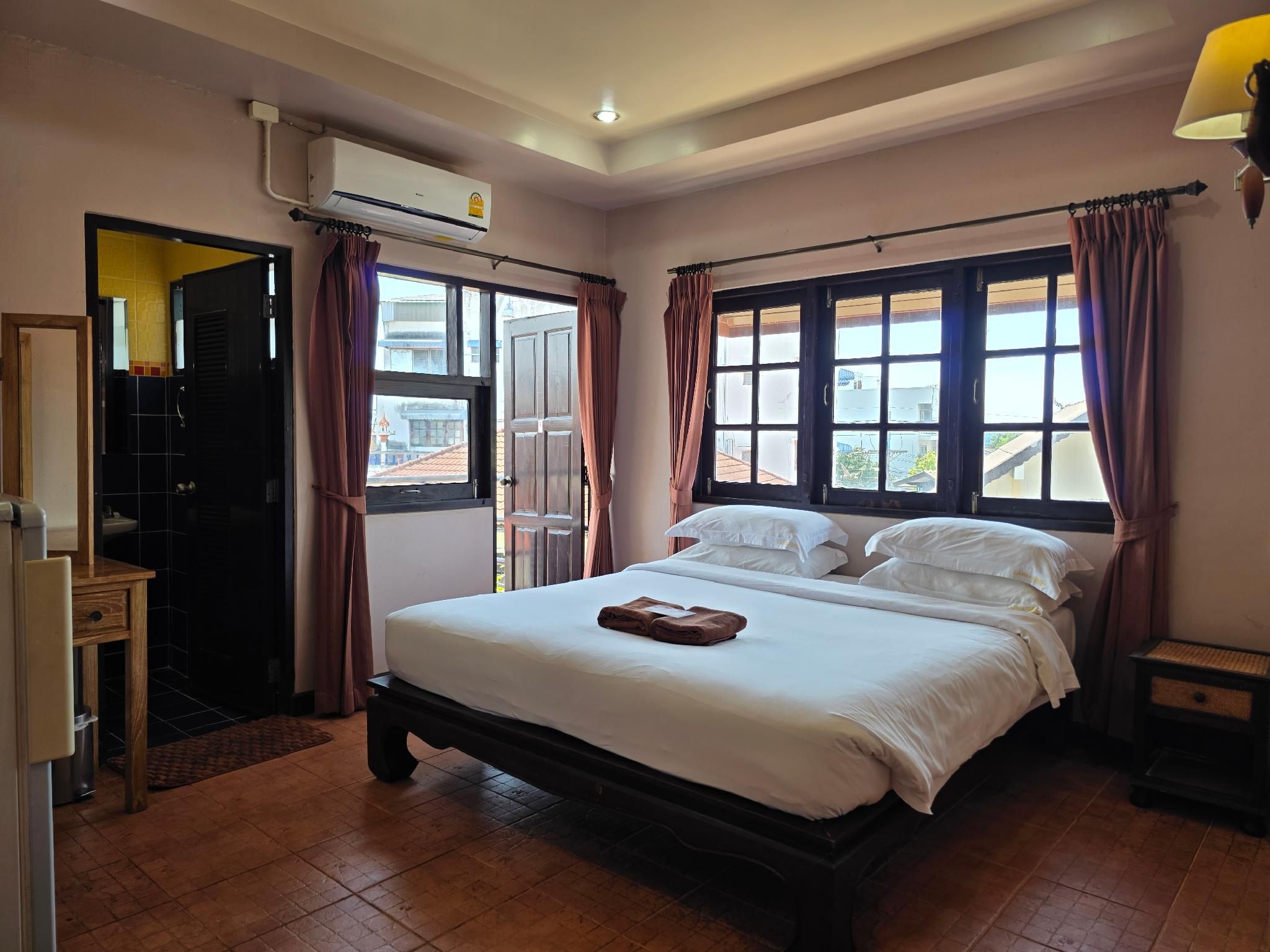 A bedroom with a bed, a window, a door, and an air conditioning unit.