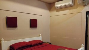 A single bed with a red bedspread, two pillows, and two towels on the bed. - Wualai Boutique by Lanna Oriental (Chiang Mai)