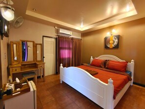 Une chambre à coucher avec un lit blanc, des rideaux marron, une commode en bois, un miroir et un climatiseur fixé au mur.