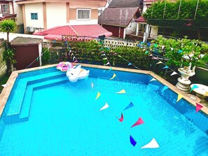 Une piscine avec des jeux gonflables, entourée de maisons et de verdure.