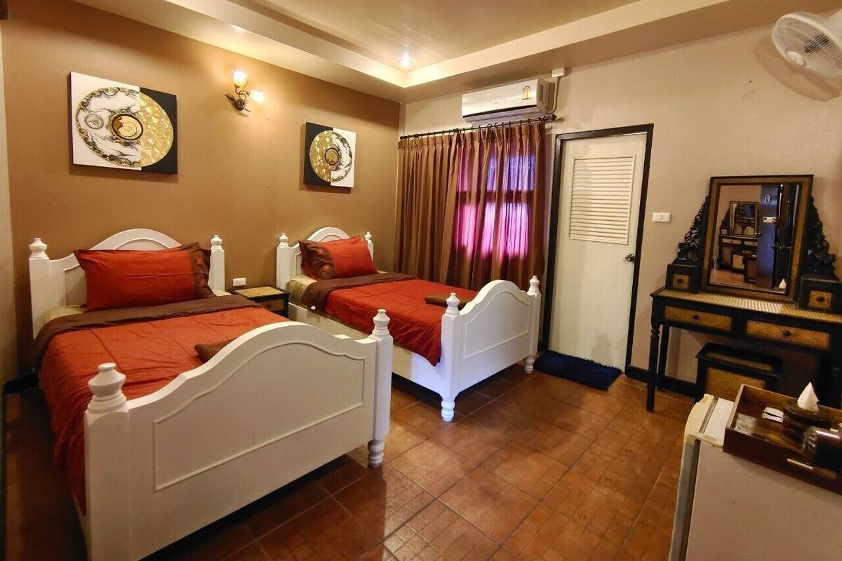 Une chambre d’hôtel avec deux lits, un bureau, un miroir et des œuvres d’art accrochées aux murs.
