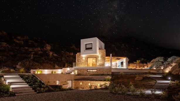 Una casa moderna con fachada de piedra, techo plano y una escalera que lleva a la entrada.