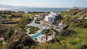 Una villa moderna con piscina, immersa nel verde e affacciata su un paesaggio costiero.
