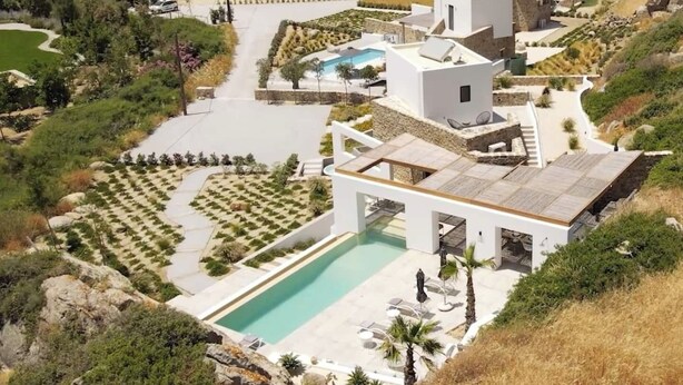 Una località balneare con architettura moderna, una piscina centrale e vista sul mare.