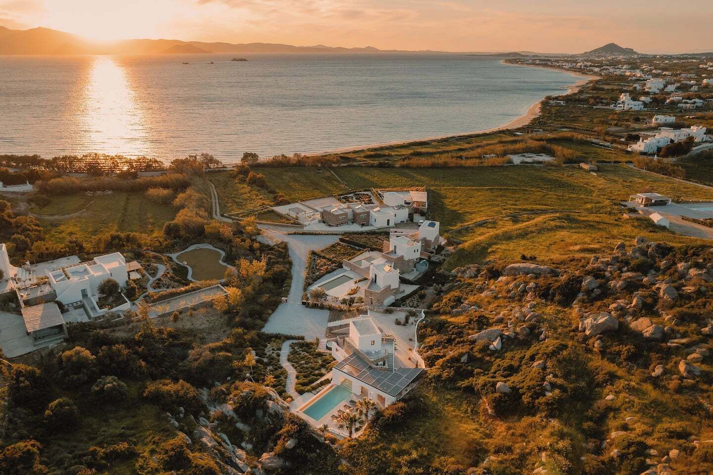A coastal property with multiple buildings, a swimming pool, and a view of the sea.