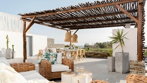 Une terrasse sur le toit, aménagée avec des meubles en osier, une table dressée pour le repas et des plantes en pot.