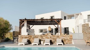 Une villa moderne dotée d’une piscine en pierre, d’un espace salon extérieur et d’une pergola.