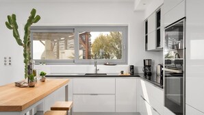 Une cuisine moderne avec un plan de travail en bois, des armoires blanches et une grande fenêtre.