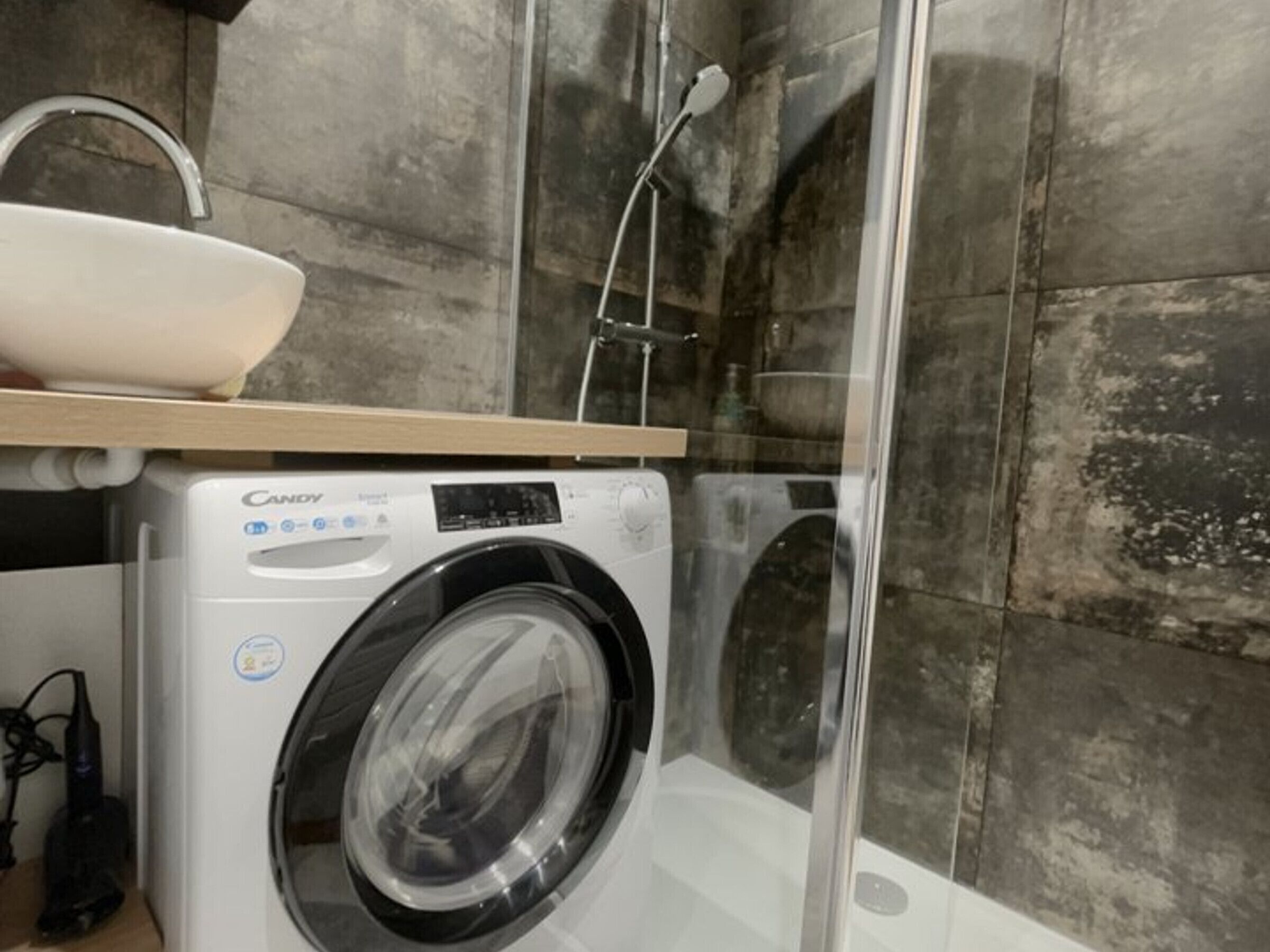 A modern bathroom with a built-in washing machine, a sink, and a shower.