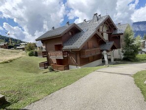 A chalet-style building with a sloped roof, wooden balconies, and a gravel driveway. - 2-Room Apartment for 6 - Ski-In/Ski-Out, Sleeps 6, Near Shops (Les Carroz d'Arâches)
