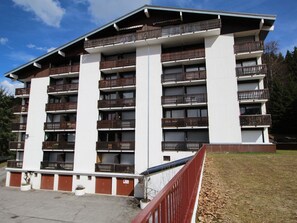 A multi-story building with balconies, a flat roof, and a parking area in front. - Studio 4 pers. near slopes and shops, balcony, parking (Les Carroz d'Arâches)