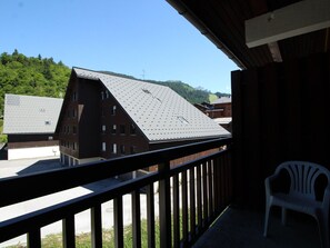 A balcony with a view of a building with a sloped roof and multiple windows. - Renovated Duplex Studio for 4/5 with Garage, Near Slopes and Shops (Les Carroz d'Arâches)