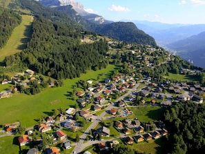 An aerial view of a residential area with houses, roads, and surrounding greenery.